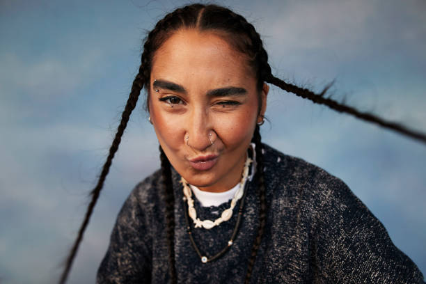 portrait of non-binary person with braided hair puckering against colored background - fashion stock pictures, royalty-free photos & images
