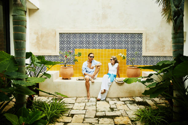 portrait of senior couple relaxing in courtyard at tropical resort - travel photos et images de collection