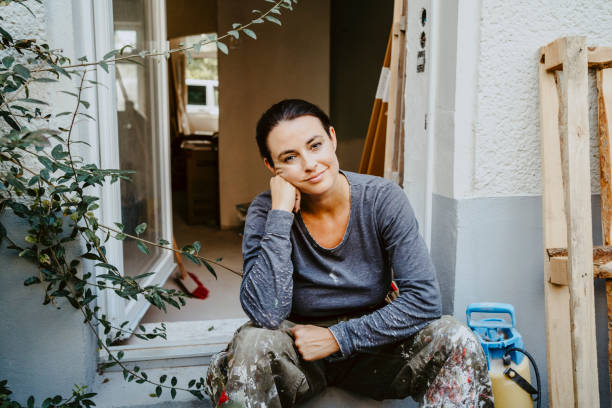 portrait of smiling female carpenter sitting at entrance of house - home decoration stock pictures, royalty-free photos & images