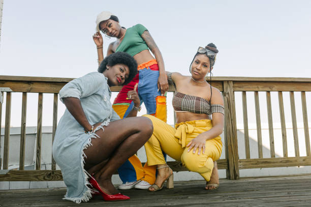 portrait of three stylish women posing on rooftop deck - fashion stock pictures, royalty-free photos & images