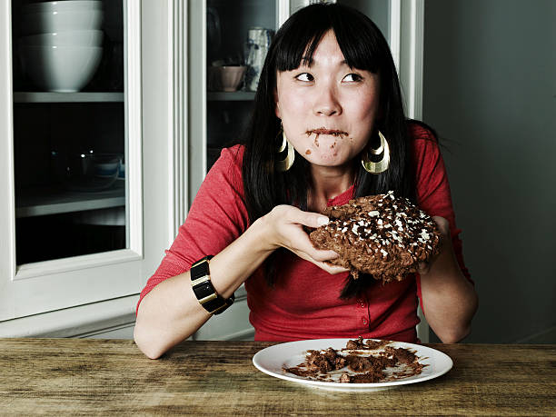 portrait of woman eating chocolate cake - junk food stock pictures, royalty-free photos & images