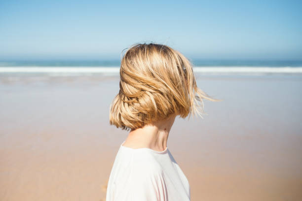 portrait of woman looking at the ocean beach. - hairstyle stock pictures, royalty-free photos & images