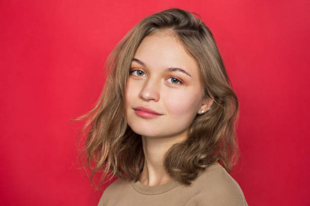 portrait of woman with light brown hair and smiling against red background - hairstyle stock pictures, royalty-free photos & images