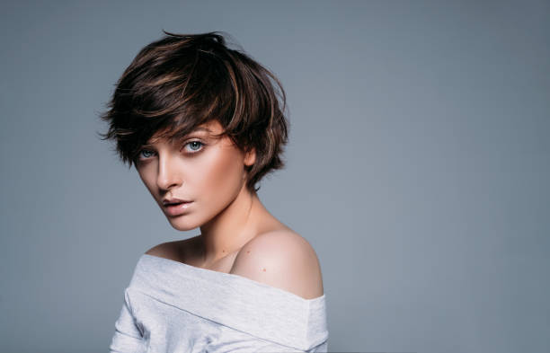 portrait of young female model with short hair on blue background - hairstyle stock pictures, royalty-free photos & images