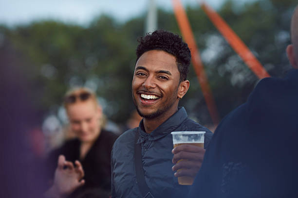 portrait of young guy at festival holding beer - concert stockfoto's en -beelden
