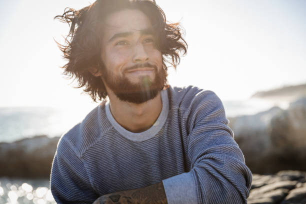 portrait of young man at beach on windy day - hairstyle stock pictures, royalty-free photos & images