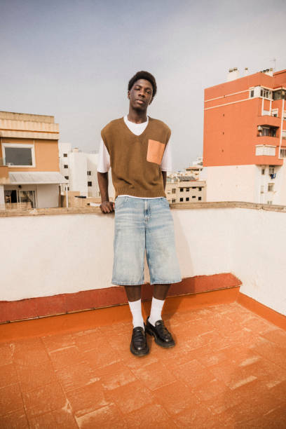 portrait of young man standing near retaining wall of building terrace - fashion stock pictures, royalty-free photos & images
