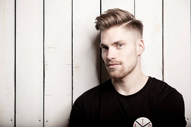 portrait of young man with quiff in front of wooden wall - hairstyle fotografías e imágenes de stock