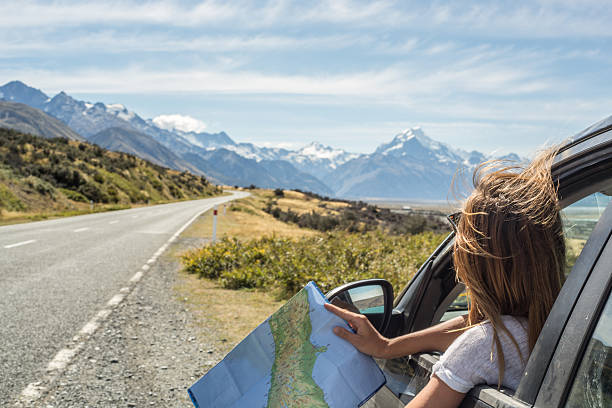 portrait of young woman in car looking at map - travel stock pictures, royalty-free photos & images