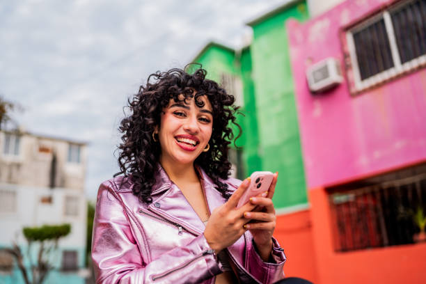 portrait of young woman using mobile phone outdoors - fashion stock pictures, royalty-free photos & images
