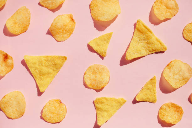 potato chips pattern over pink background, hard light with shadows. unhealthy junk food concept. - junk food stock pictures, royalty-free photos & images