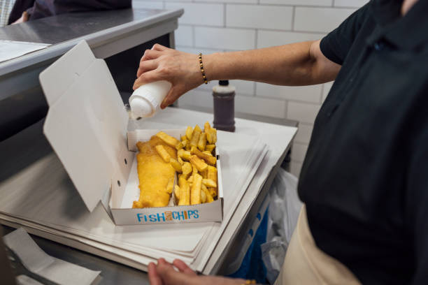 pouring salt on fish and chips - junk food stock pictures, royalty-free photos & images