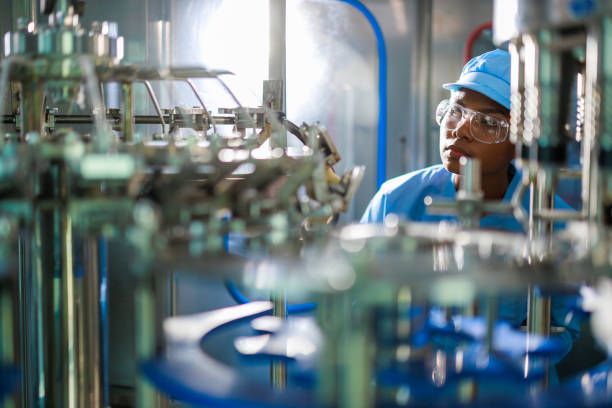 precision in progress: african female engineer in professional uniform working with digital tablet overseeing quality control in beverage manufacturing facility - food stock pictures, royalty-free photos & images