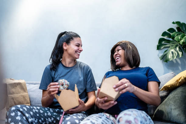 pregnant lesbian couple talking while eat in the living room at home - junk food stock pictures, royalty-free photos & images