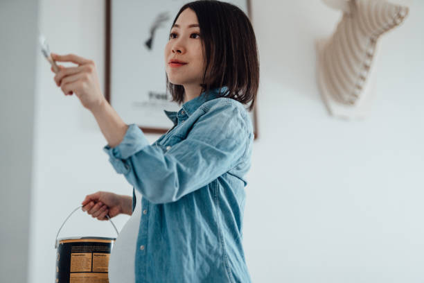 pregnant woman painting nursery room - home decoration stock pictures, royalty-free photos & images