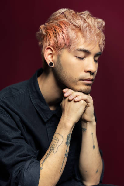 primer plano de un joven reflexivo con las manos entrelazadas - hairstyle fotografías e imágenes de stock
