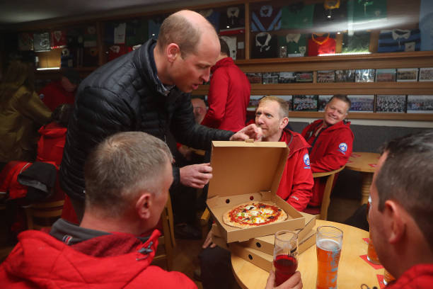 Prince William, Prince of Wales delivers take-away pizzas from a pizza van to members of the Mountain Rescue team, during a visit the Dowlais Rugby...