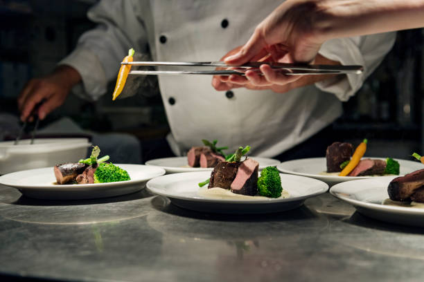 professional chef at work in a busy kitchen getting ready for service - food stock pictures, royalty-free photos & images