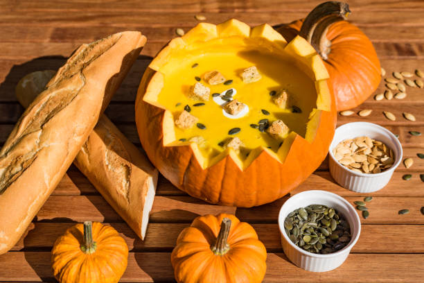 pumpkin soup in shell served with bread and roasted pumpkin seeds - food stock pictures, royalty-free photos & images
