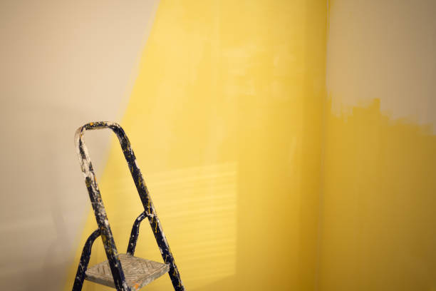 rear view of young man painting wall with yellow paint roller at home - home decoration stock pictures, royalty-free photos & images