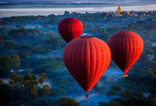 red hot air balloons over jungle, nyaung-u, mandalay region, myanmar - travel stock-fotos und bilder
