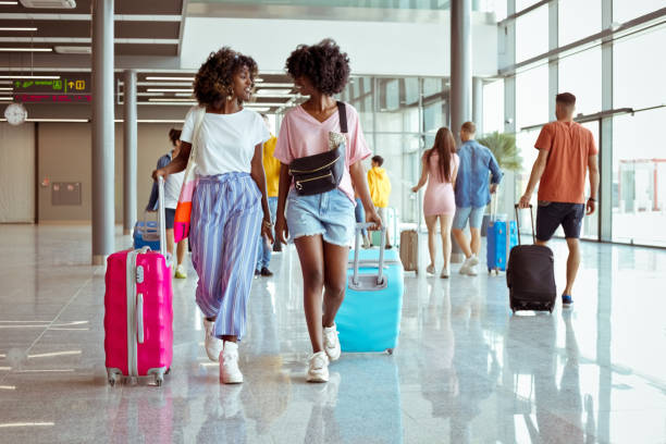 reisende, die mit gepäck am flughafen spazieren gehen - travel stock-fotos und bilder