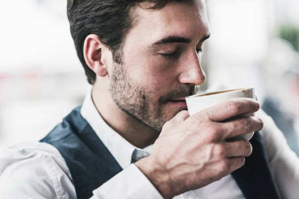 relaxed young man drinking cup of coffee - coffee stockfoto's en -beelden