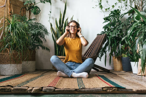 relaxed young woman sitting on the floor at home listening to music - home decoration stock pictures, royalty-free photos & images
