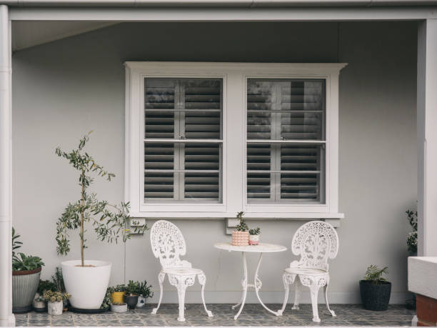 relaxing area with table set and flower pot near window in patio, garden, grey and white background - garden decoration stock pictures, royalty-free photos & images