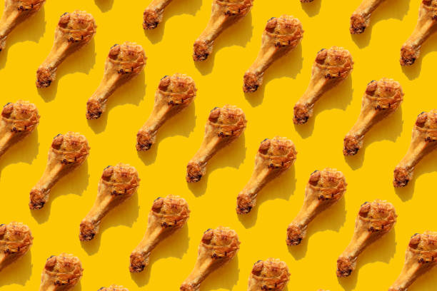 repeated fried chicken legs on the yellow background - junk food stock pictures, royalty-free photos & images