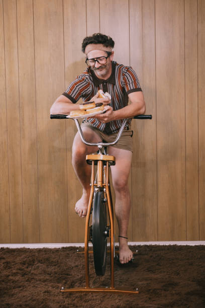 retro nineteen eighties aesthetic exercise bike man with donuts - junk food stock pictures, royalty-free photos & images