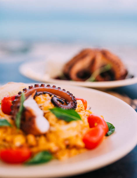 risotto with octopus tentacle and a grilled octopus served on the table - food stock pictures, royalty-free photos & images