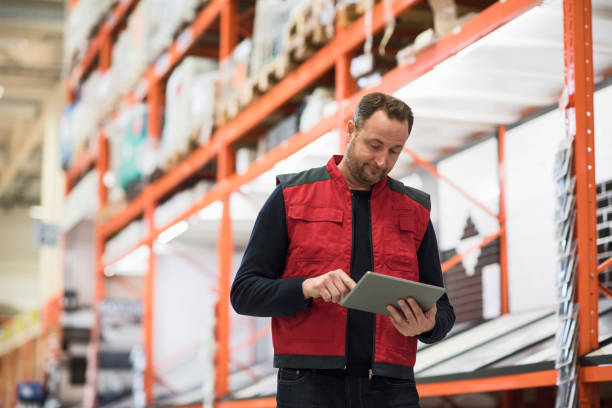 salesman using digital tablet while standing by shelf in hardware store - home decoration stock pictures, royalty-free photos & images