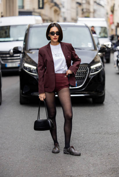 Sara Legge wears burgundy shorts, blazer, tights, black bag outside Lacoste during Womenswear Spring/Summer 2025 as part of Paris Fashion Week on...