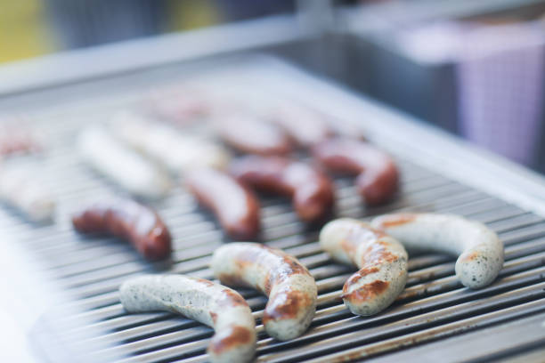 sausages grilling on a barbecue - junk food stock-fotos und bilder