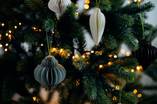 scandinavian christmas paper honeycomb ornament on christmas tree with lights. modern christmas decoration. - home decoration stock pictures, royalty-free photos & images