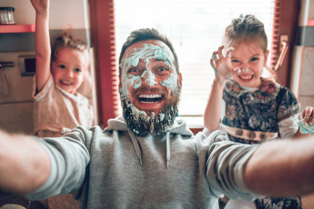 selfie by father with cute child daughters after cooking and making mess with topping - food stock pictures, royalty-free photos & images