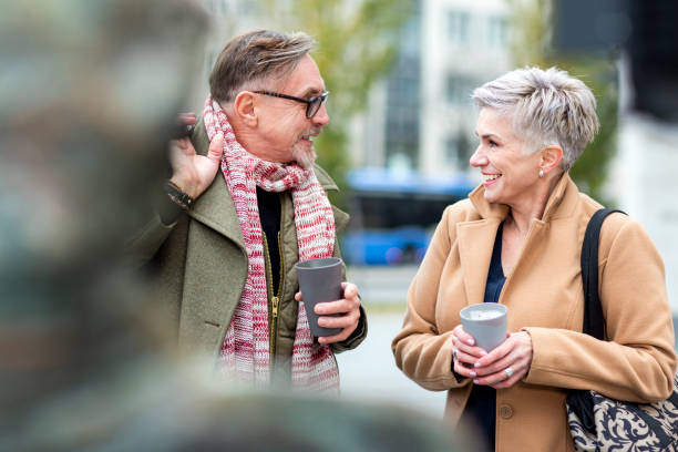 senior couple enjoying coffee to go and talking - junk food stock pictures, royalty-free photos & images