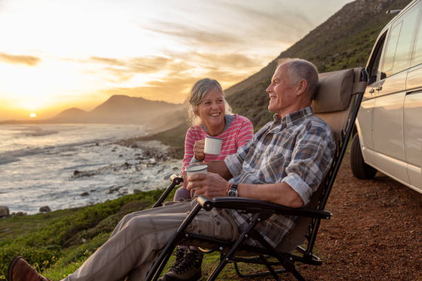 senior couple enjoying sunset by the sea - travel photos et images de collection
