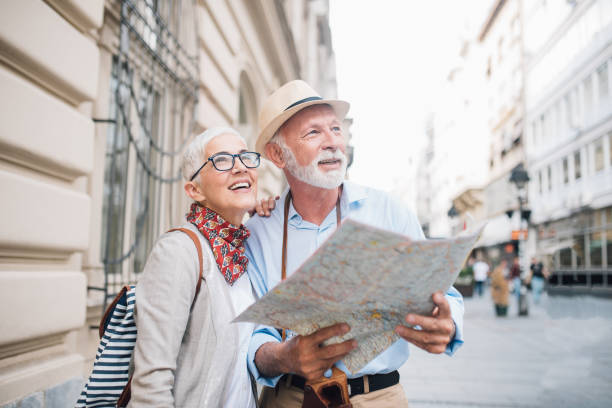 senior couple holding a map and looking at distance - travel stock pictures, royalty-free photos & images