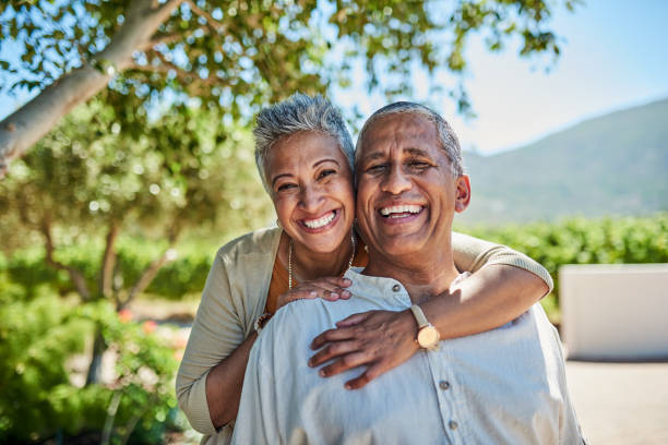 senior couple, smile and outdoor in nature park showing love, care and happy on a retirement holiday on summer day. portrait of elderly man and woman together for fresh air and tree view on vacation - travel stock pictures, r