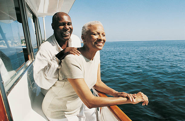 senior couple standing on deck on a boat looking at the view - travel stock pictures, royalty-free photos & images