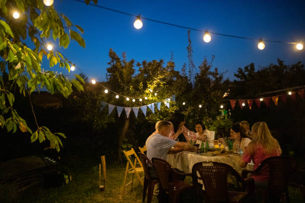 senior friends enjoying quality time together on party at backyard during night - garden decoration stock pictures, royalty-free photos & images