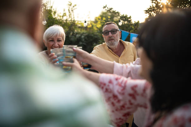 senior friends toasting for their long friendship during party at backyard - garden decoration stock pictures, royalty-free photos & images