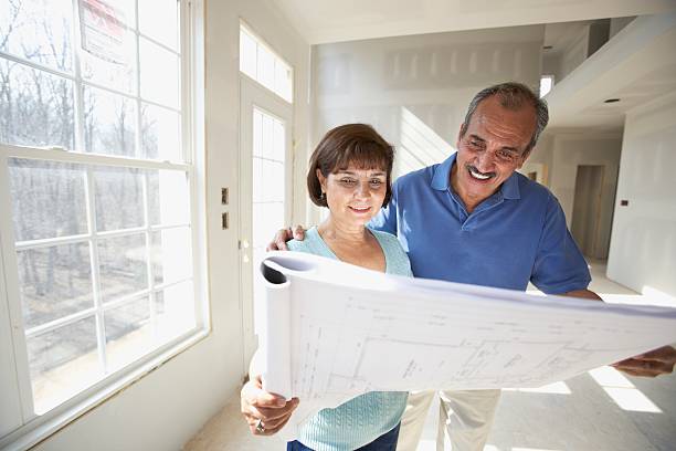 senior hispanic couple looking at blueprints in new house - home decoration stock pictures, royalty-free photos & images