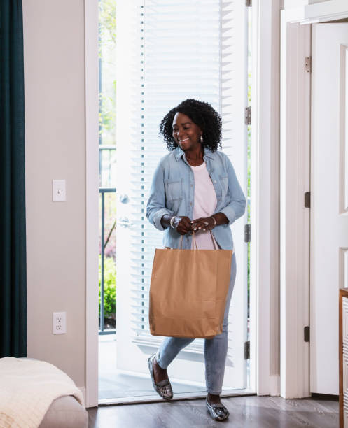 senior woman carrying shopping bag home, thru front door - junk food stock pictures, royalty-free photos & images