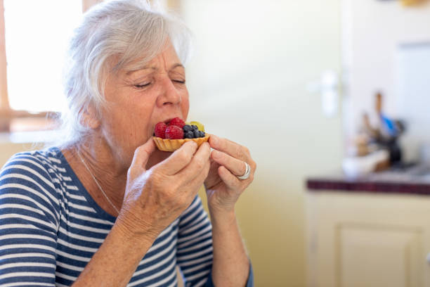senior woman enjoying eating a fruit tart - junk food stock pictures, royalty-free photos & images