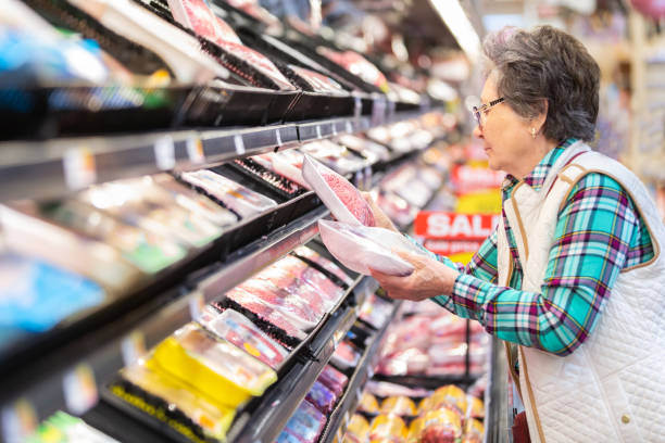 senior woman selecting ground beef in the meat department. - food stock pictures, royalty-free photos & images