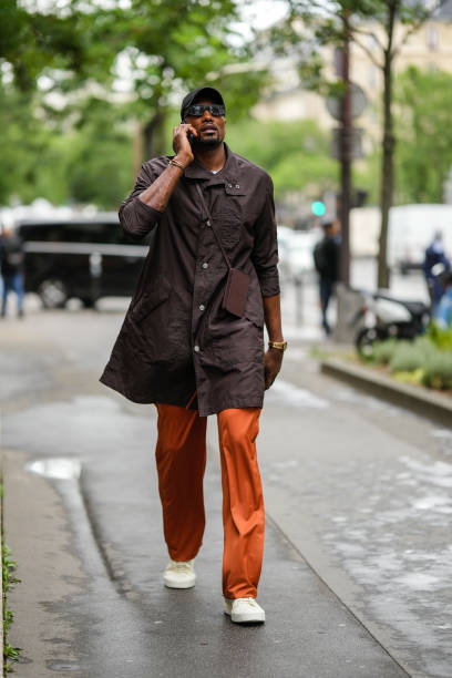 Serge Ibaka wears a black cap, black sunglasses, a white t-shirt, a dark brown long shirt, a gold Juste Un Clou bracelet from Cartier, a silver...