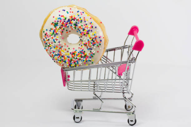 shopping cart with a colorful donut - junk food stockfoto's en -beelden